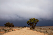 Dirt Road In Rural Landscape With Approaching Storm