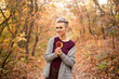 © Marharyta - stylish woman with autumn leaf in autumn forest background with golden and red trees