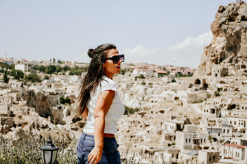 Back view of young  Happy tourist woman enjoying and photographing  the beautiful  Pigeon valley in Cappadocia Turkey with amazing rock formations and fairy chimneys at Goreme National park