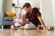 © Arsenii - Cute adorable baby boy with blond hair playing sorter sitting on floor with his father in living-room, spending time together after napping. Caring daddy. Dad playing with his son using education toys