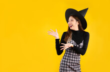 Young Asian Woman In Halloween Costume Wearing Witch Hat Posing Hand Pointing On Yellow Background.