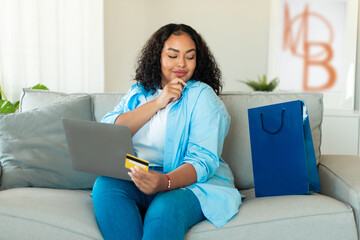 Wall Mural - African Lady Holding Credit Card Using Laptop Shopping At Home