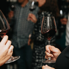 Wall Mural - Red wine by the glass at a tasting of white, rosé and red wines that celebrates friendship and joy at the highest level with your best friends on a weekend evening full of people from social media.