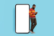 Mobile Offer. Smiling Blank Man With Smartphone Standing Near Big Blank Telephone