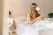 © Timm Creative - Happy woman having coffee and using phone in bed