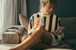 © Timm Creative - Happy woman having coffee and using phone on sofa