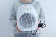 Caucasian woman holding a fan heater close-up..