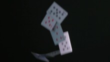 Drop a deck of playing cards on a black background. Flying solitaire cards in slow motion.