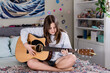 © Austockphoto - teen girl playing guitar in her bedroom