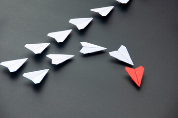 Wall Mural - Red paper plane origami leading white planes on dark background. Leadership skills concept