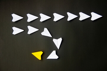 Wall Mural - Yellow paper plane origami leading white planes on dark background. Leadership skills concept