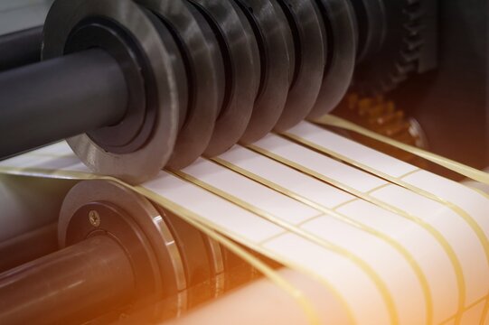Rotating knives for cutting a self-adhesive label into several narrow ribbons. Equipment for the production of self-adhesive labels. Rotary die cutting machine with slitting blade. Selective focus