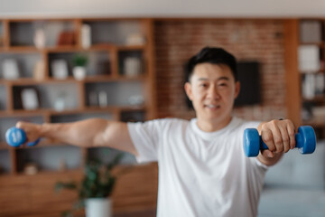 Wall Mural - Sporty korean mature man exercising with dumbbells at home, strengthening arm muscles, selective focus on hand