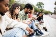© Xavier Lorenzo - Group of multiracial young friends using smartphone outdoor - Addicted millennial people sharing social media content on mobile phone app