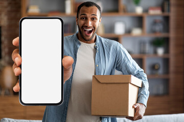 Delivery Service App. Excited black man holding box and showing blank smartphone