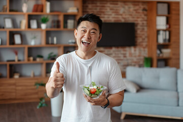 Fitness nutrition. Happy asian mature man holding bowl with fresh vegetable salad and showing thumb up