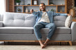 © Prostock-studio - Home Relax. Handsome Black Man Sitting On Couch And Switching Tv Channels