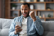 © Prostock-studio - Online Win. Overjoyed Young Black Man Looking At Smartphone Screen With Excitement
