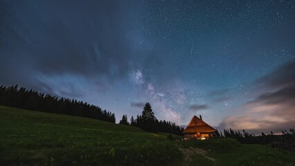 Wall Mural - clouds and milky way galaxy stars motion fast over wooden hut in wild forest nature, night to day ti