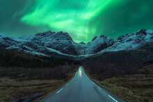 Car On Road Under Green Northern Lights At Night