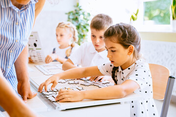 Creativity and logical thinking. Children primary school at classroom actively learn the basics of programming with special puzzles.