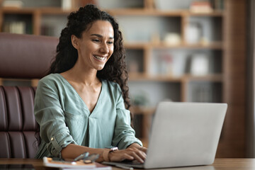 Wall Mural - Positive young woman freelancer using laptop at home