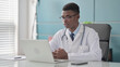 © stockbakers - Young African Doctor Talking on Video Call on Laptop in Office