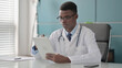 © stockbakers - Young African Doctor using Tablet while Sitting in Office