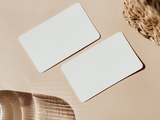 Wall Mural - Two blank white cards, basket and glass of water on beige background top view.