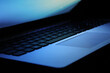 © Pikselar - Closeup dark laptop keyboard with gradient blue screen light reflected