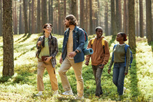 Group Of Friends Smiling And Talking While Walking Together In The Forest During Their Hiking