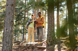 © Seventyfour - Multiethnic young couple using mobile phone together standing on hill in the forest