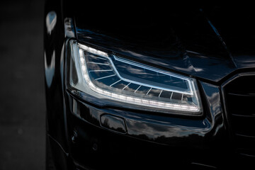 Wall Mural - Headlight of Modern Prestigious Black Car Close Up.