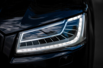 Wall Mural - Headlight of Modern Prestigious Black Car Close Up.