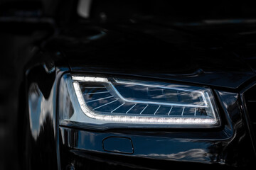 Wall Mural - Headlight of Modern Prestigious Black Car Close Up.