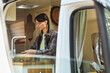 © Seventyfour - Young woman in eyeglasses washing vegetables under water in sink while standing in the van during camping