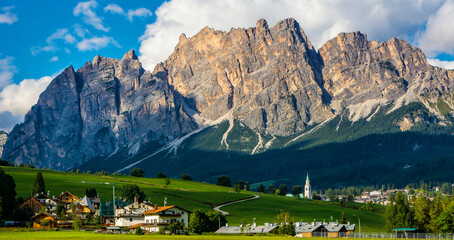 Wall Mural - Beautiful view of Cortina d'Ampezzo town with alpine green landscape and massive Dolomites Alps in the background. Province of Belluno, South Tyrol, Italy. Artistic picture. Beauty world