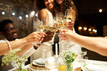 Wall Mural - Hands of wedding guests and two intercultural brides clinking with flutes of champagne over festive table while enjoying party