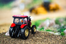Orange Toy Tractor Laying On The Ground In The Garden Where The Background Was Blurred.