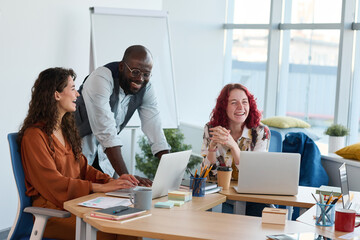 Leinwandbilder - Three young multicultural employees laughing at working meeting in office during discussion of new ideas or points of project