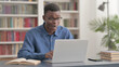 © stockbakers - Young African Man Celebrating Success while using Laptop in Office