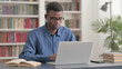 © stockbakers - Young African Man Working on Laptop in Office