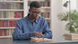© stockbakers - Young African Man Reading Book in Library
