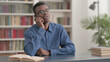 © stockbakers - Young African Man Talking on Phone in Office