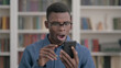 © stockbakers - Young African Man Reacting to Loss on Smartphone