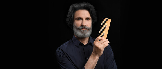 Wall Mural - Mature male hairdresser with comb on dark background