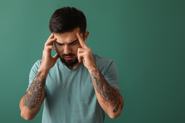 Poster - Young bearded man with headache on green background