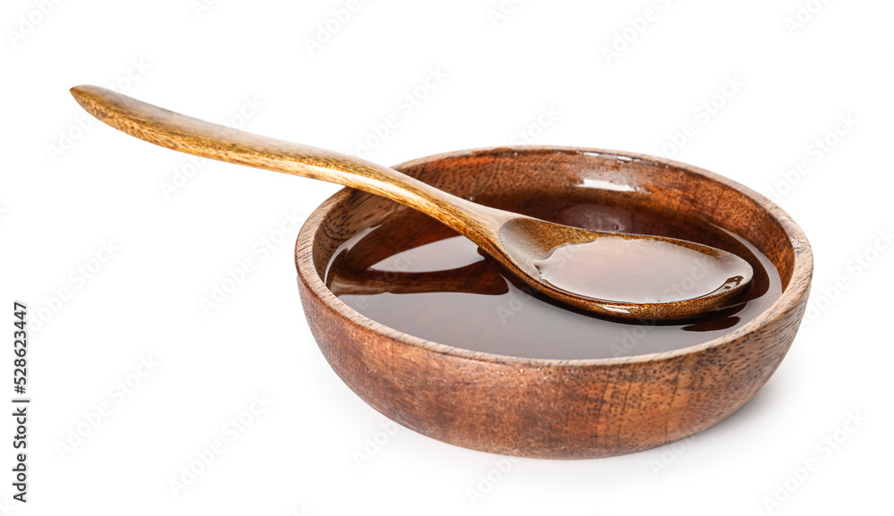 Wooden bowl and spoon with tasty maple syrup on white background
