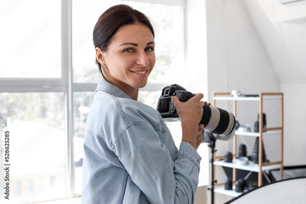 Female photographer with professional camera working in studio