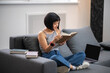 © zinkevych - A short-haired young woman reading a book while sitting on the sofa